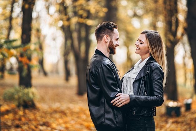 Lindo casal jovem andando no parque outono em um dia ensolarado