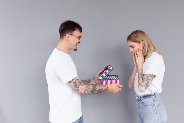 Lindo casal jovem apaixonado em casa comemorando com uma caixa de presente e flores