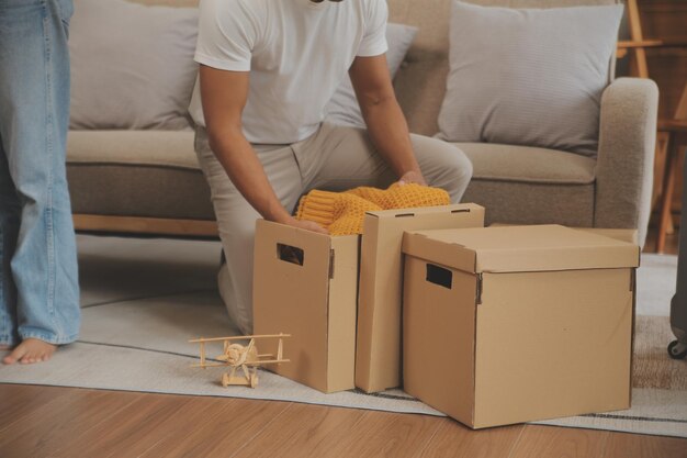 Lindo casal jovem apaixonado se divertindo desempacotando coisas de caixas de papelão enquanto moravam juntos em seu novo apartamento