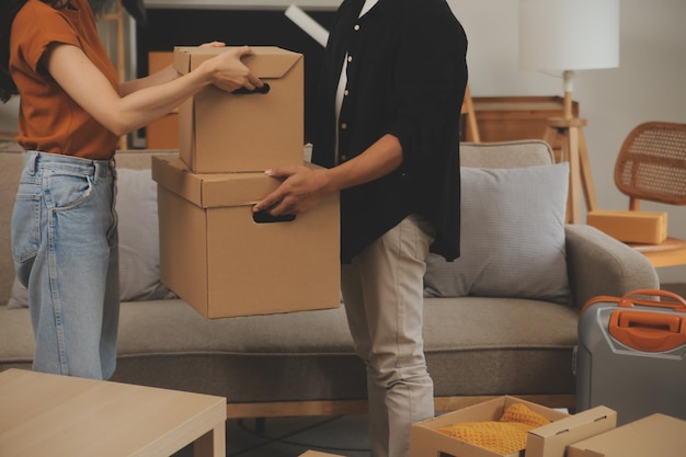 Lindo casal jovem apaixonado se divertindo desempacotando coisas de caixas de papelão enquanto moravam juntos em seu novo apartamento