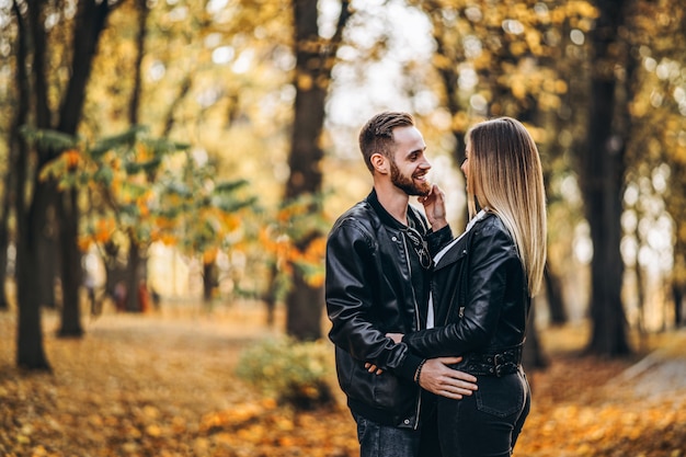 Lindo casal jovem caminhando no parque de outono em um dia ensolarado