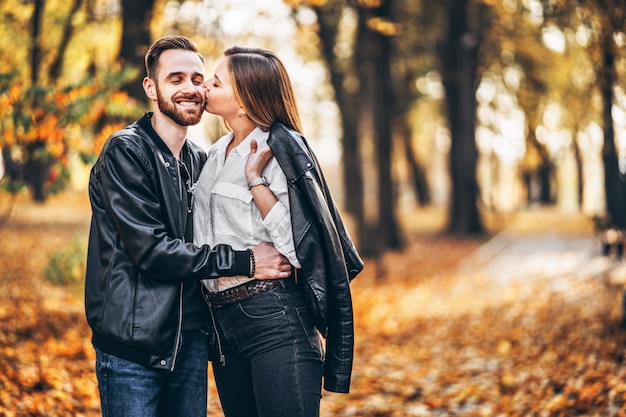 Lindo casal jovem caminhando no parque de outono em um dia ensolarado