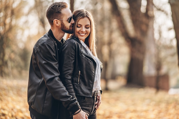 Lindo casal jovem caminhando no parque de outono em um dia ensolarado