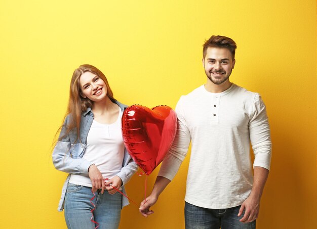 Lindo casal jovem com balão em forma de coração na cor de fundo