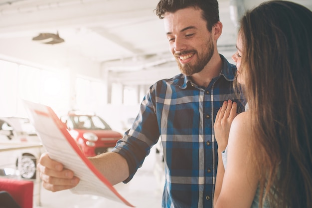 Foto lindo casal jovem dançando na concessionária escolhendo o carro para comprar