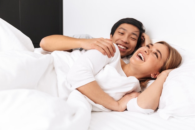 Lindo casal jovem, deitado na cama, rindo