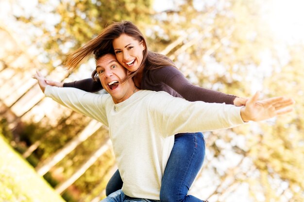 Foto lindo casal jovem desfrutando de uma carona no parque. olhando para a câmera e sorrindo.