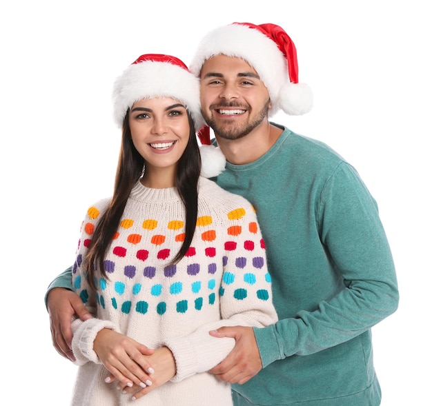 Lindo casal jovem em chapéus de Papai Noel na celebração de Natal de fundo branco