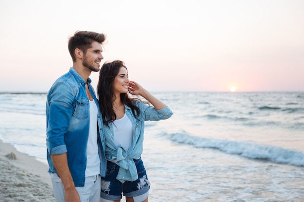 Lindo casal jovem em pé na praia