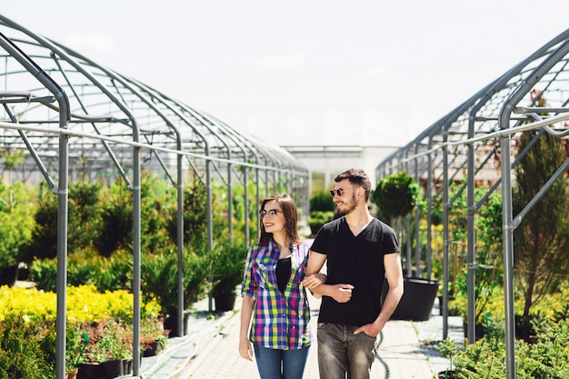 Lindo casal jovem em roupas casuais é escolher plantas e sorrindo