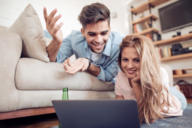 Lindo casal jovem em roupas casuais está usando um laptop