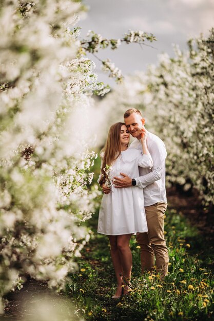 Lindo casal jovem em um lugar romântico, pomar de maçã florescendo primavera. Casal feliz e alegre se diverte enquanto caminhava no jardim. Homem segurando a mão de uma mulher