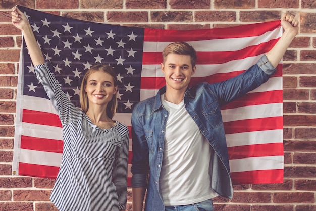 Lindo casal jovem está segurando a bandeira americana