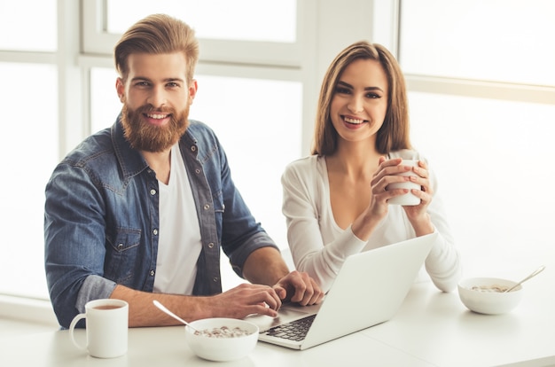 Lindo casal jovem está usando um laptop.