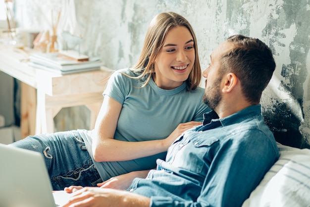 Lindo casal jovem fica em casa na quarentena e sorrindo um para o outro