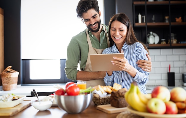 Lindo casal jovem na cozinha enquanto cozinha