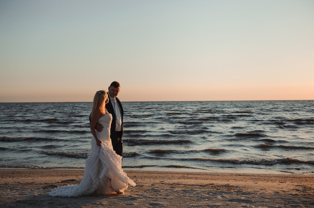 Lindo casal jovem na praia ao pôr do sol.