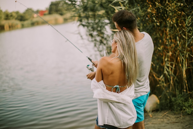Lindo casal jovem pescar juntos por um lago