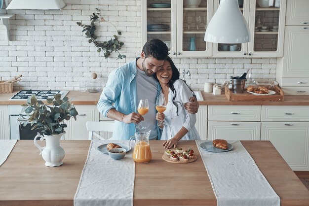 Lindo casal jovem preparando o café da manhã enquanto passa algum tempo na cozinha doméstica