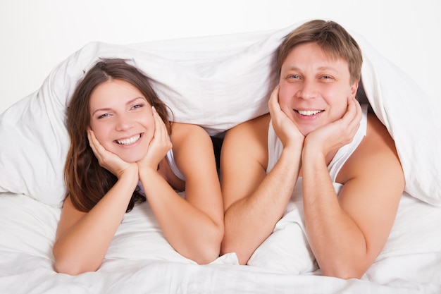 Lindo casal jovem relaxando na cama em casa sobre o branco