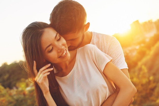 Lindo casal jovem se abraçando e sorrindo enquanto passa o tempo ao ar livre