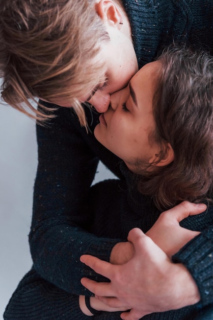 Lindo casal jovem se beijando dentro de casa no estúdio.