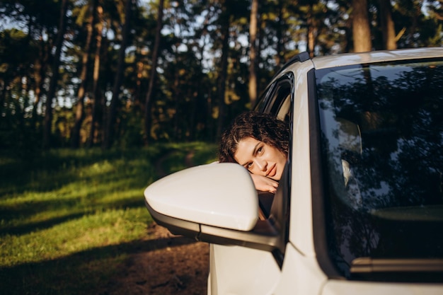 Lindo casal jovem sentado nos bancos do passageiro da frente e sorrindo enquanto homem bonito dirigindo um carro