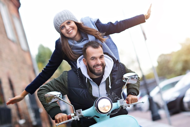 Foto lindo casal jovem sorrindo enquanto andava de scooter na cidade no outono