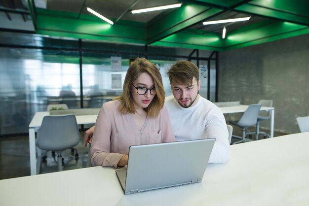 Lindo casal jovem trabalhando com um laptop em um elegante