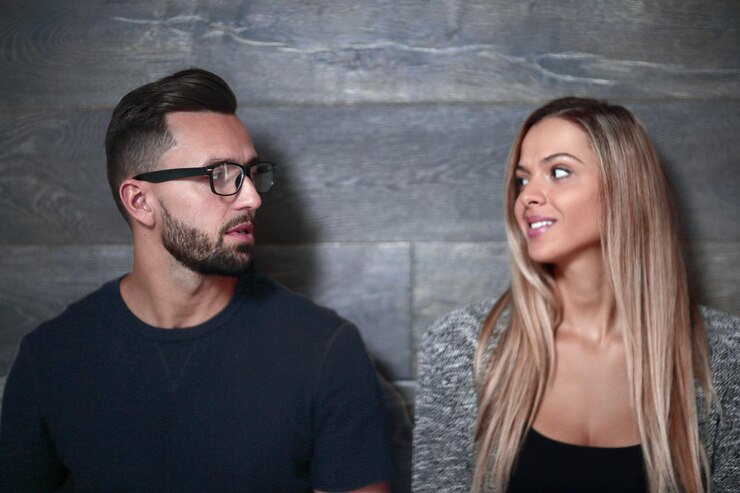Foto lindo casal parece reto e sorrindo em pé em linha reta no fundo cinza