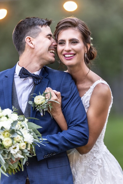 Lindo casal recém-casado ri e se abraça no dia do casamento após a cerimônia