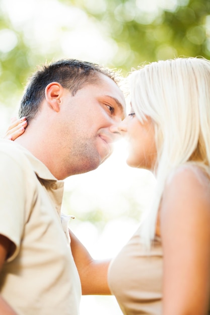 Foto lindo casal romântico abraçado no parque se beijando na frente da luz do sol.