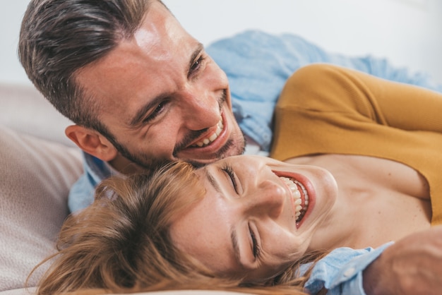 Lindo casal romântico se divertindo rindo juntos assistindo televisão. jovens apaixonados em casa a passar tempo juntos.