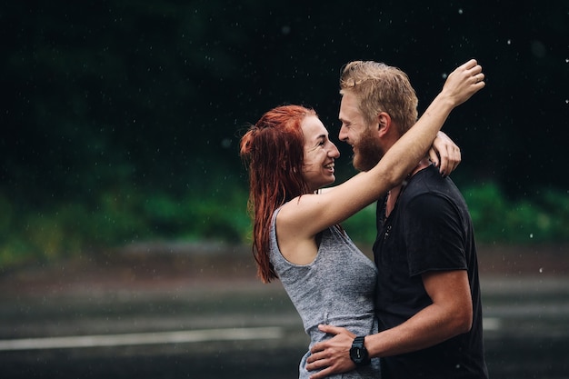 Lindo casal se abraçando do lado de fora na chuva