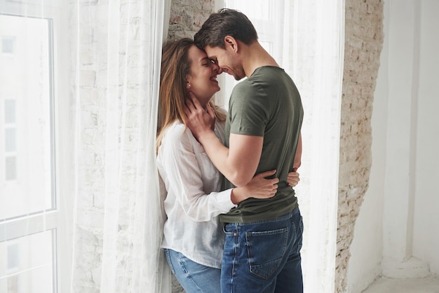 Lindo casal se beijando e curtindo perto da janela de sua nova casa.