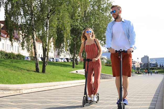 Lindo casal se divertindo dirigindo scooter elétrico pela cidade.