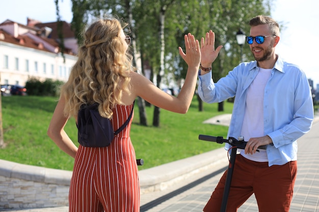 Lindo casal se divertindo dirigindo scooter elétrico pela cidade.