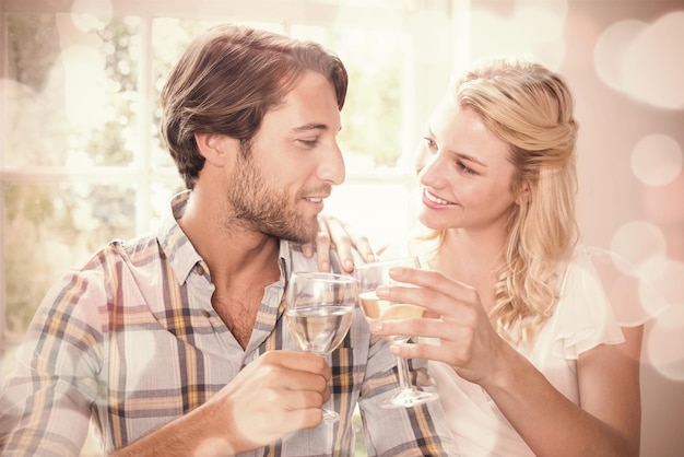 Lindo casal sorridente desfrutando de vinho branco juntos em casa na sala de jantar