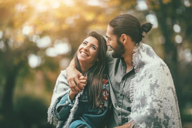 Lindo casal sorridente desfrutando no parque da cidade ensolarada em cores de outono, olhando um ao outro.