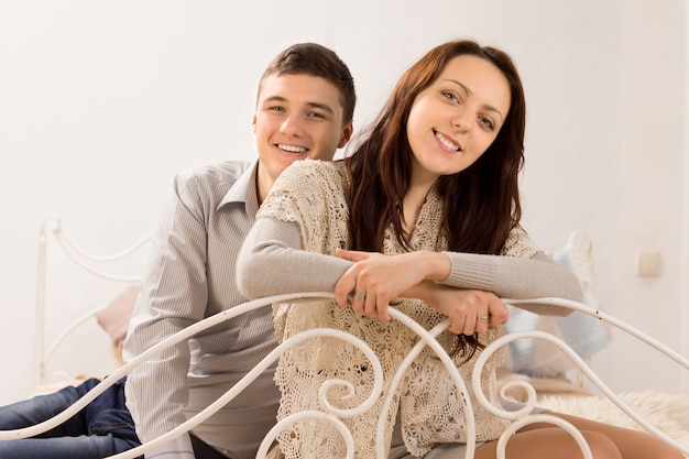 Lindo casal sorridente em uma cama de ferro forjado