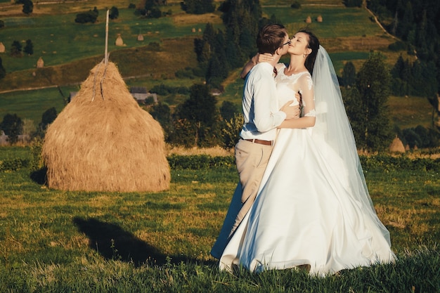 Lindo casamento nas montanhas, um jovem casal feliz perto do palheiro.