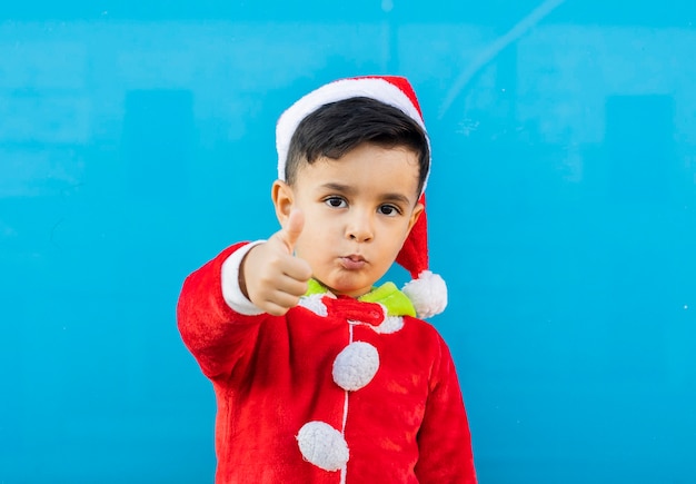 Lindo chapéu de papai noel de menino, gesto de ok, fundo azul