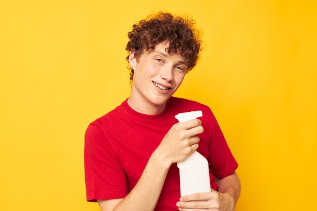 Lindo chico pelirrojo en una camiseta roja detergentes en manos posando tiro monocromo