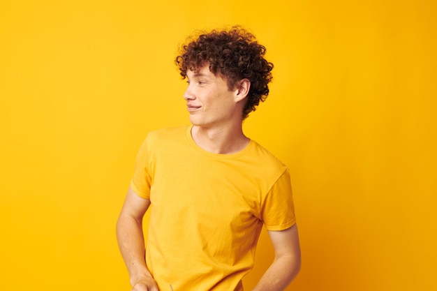 Lindo chico pelirrojo con gafas elegantes camiseta amarilla posando fondo amarillo inalterado