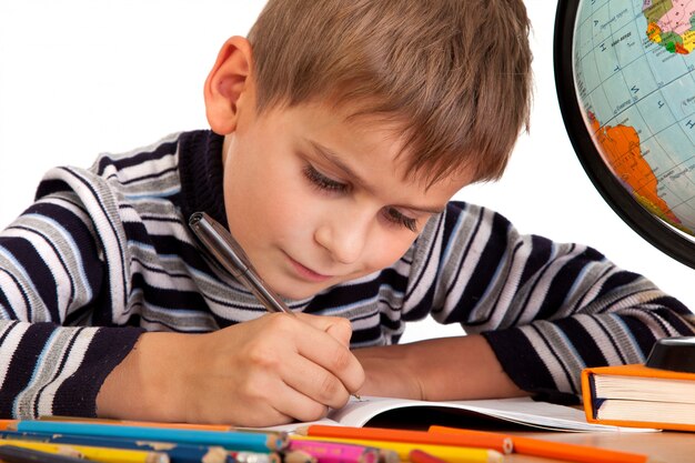 Foto lindo colegial escribiendo en un cuaderno