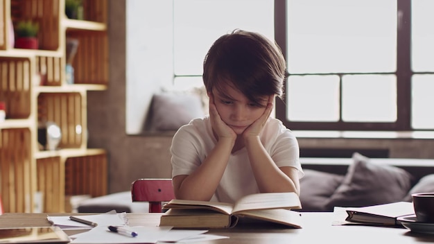 Lindo colegial leyendo un libro en casa