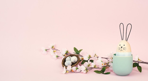 Lindo conejito o conejo con flores de cerezo y un nido de huevos de Pascua, tarjeta de felicitación de vacaciones de primavera