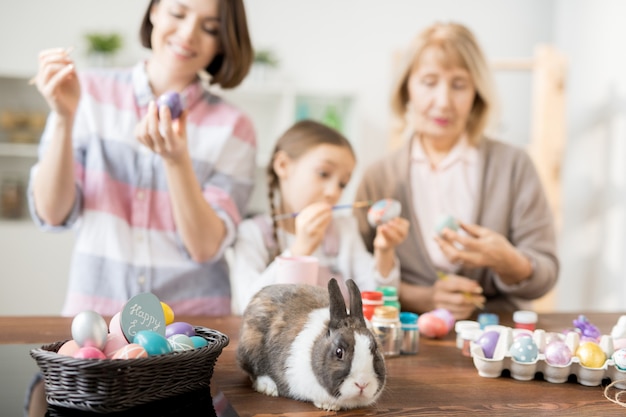 Lindo conejito de Pascua y coloridos huevos en la cesta listos para vacaciones