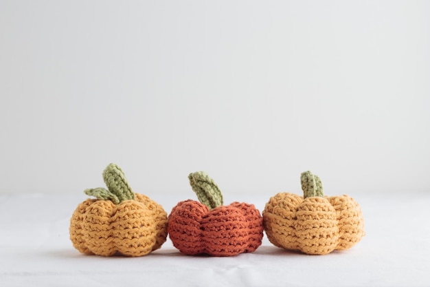 Lindo crochet tejido calabazas amarillas y naranjas sobre fondo blanco.