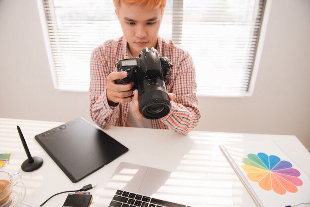 Lindo designer gráfico masculino olhando fotos em uma câmera digital no escritório